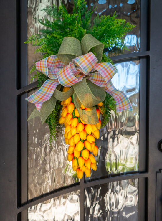 Orange tulips arranged to create a carrot shaped door wreath for Easter