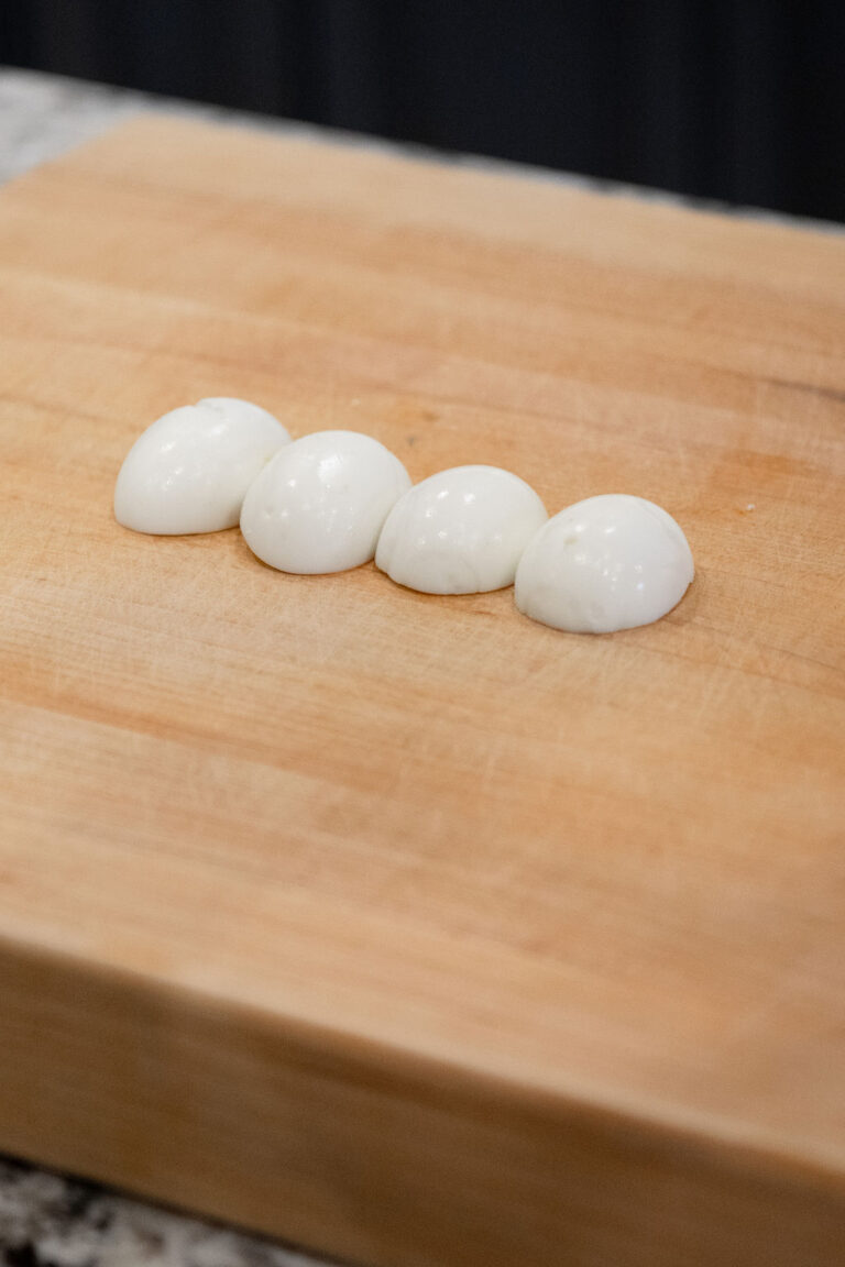 Halved boiled eggs on a chopping block.