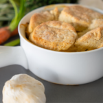 Homemade chicken pot pie with a biscuit crust in a white ceramic dish