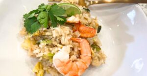 Crab fried rice with pineapple garnished with lime, cilantro, and shrimp.